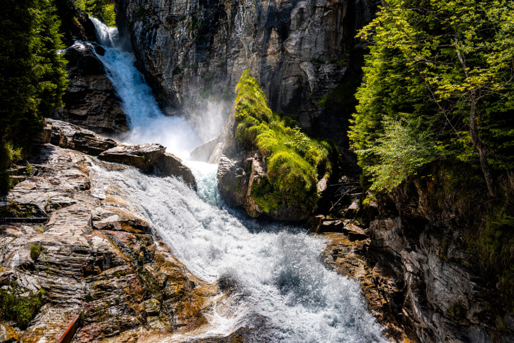 Powerful waterfall in Bad Hofgastein surrounded by alpine cliffs and forest in the Austrian Alps