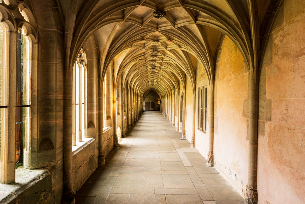 Long Gothic cloister corridor at Bebenhausen Abbey with vaulted ceilings, stone arches, and medieval monastery architecture.