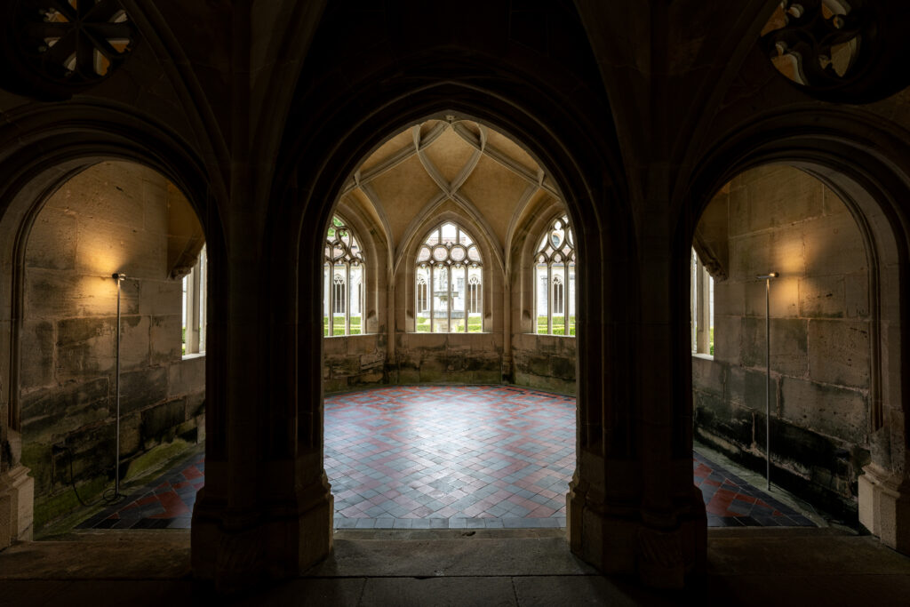 Gothic stone arches inside Bebenhausen Abbey framing a medieval chamber with vaulted ceilings and historic monastery architecture.