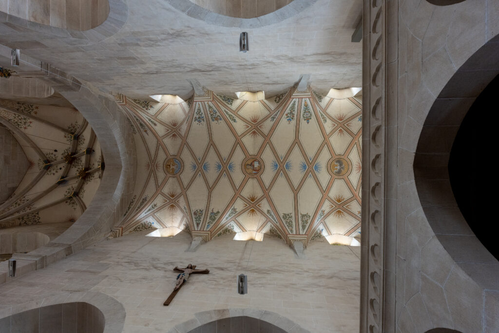 Painted Gothic vaulted ceiling inside Bebenhausen Abbey featuring medieval architecture, decorative patterns, and symmetrical stone arches.