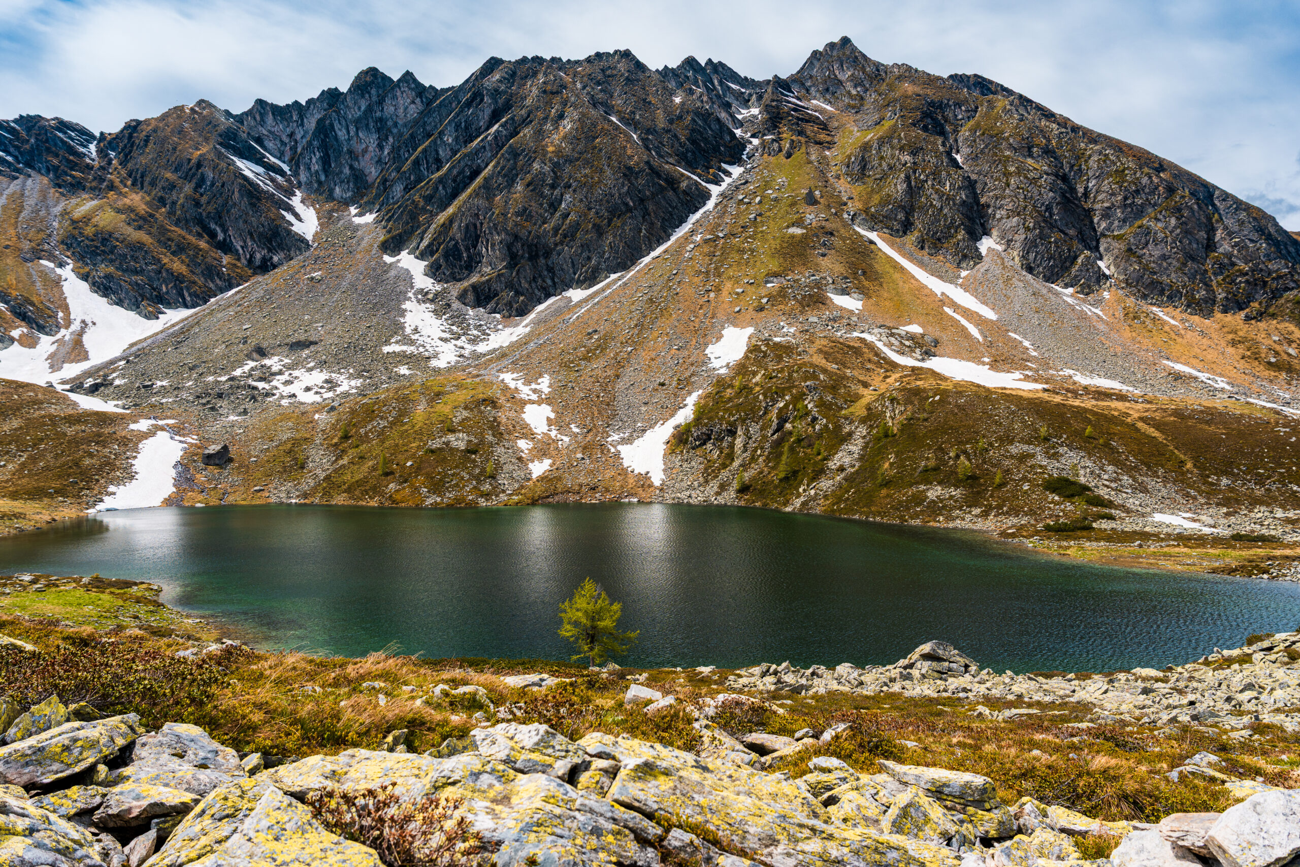 Panoramic view of Palfnersee above Bad Hofgastein with alpine mountains, crystal-clear lake and remaining June snow in the Austrian Alps.