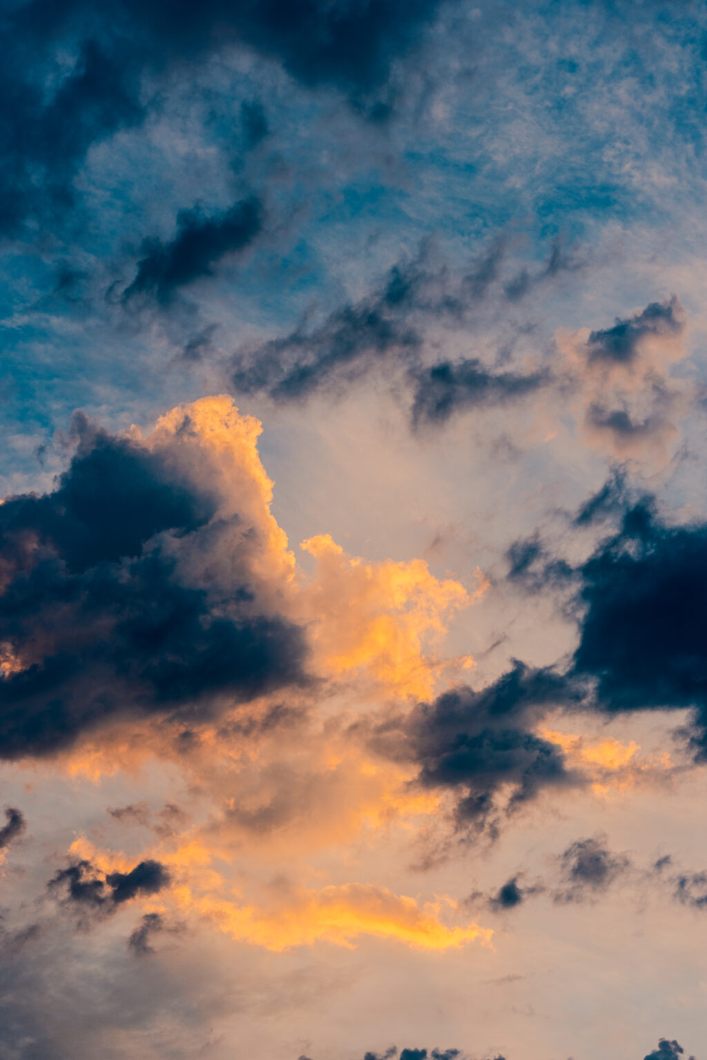 Golden sunlight illuminating dramatic clouds against a blue evening sky.