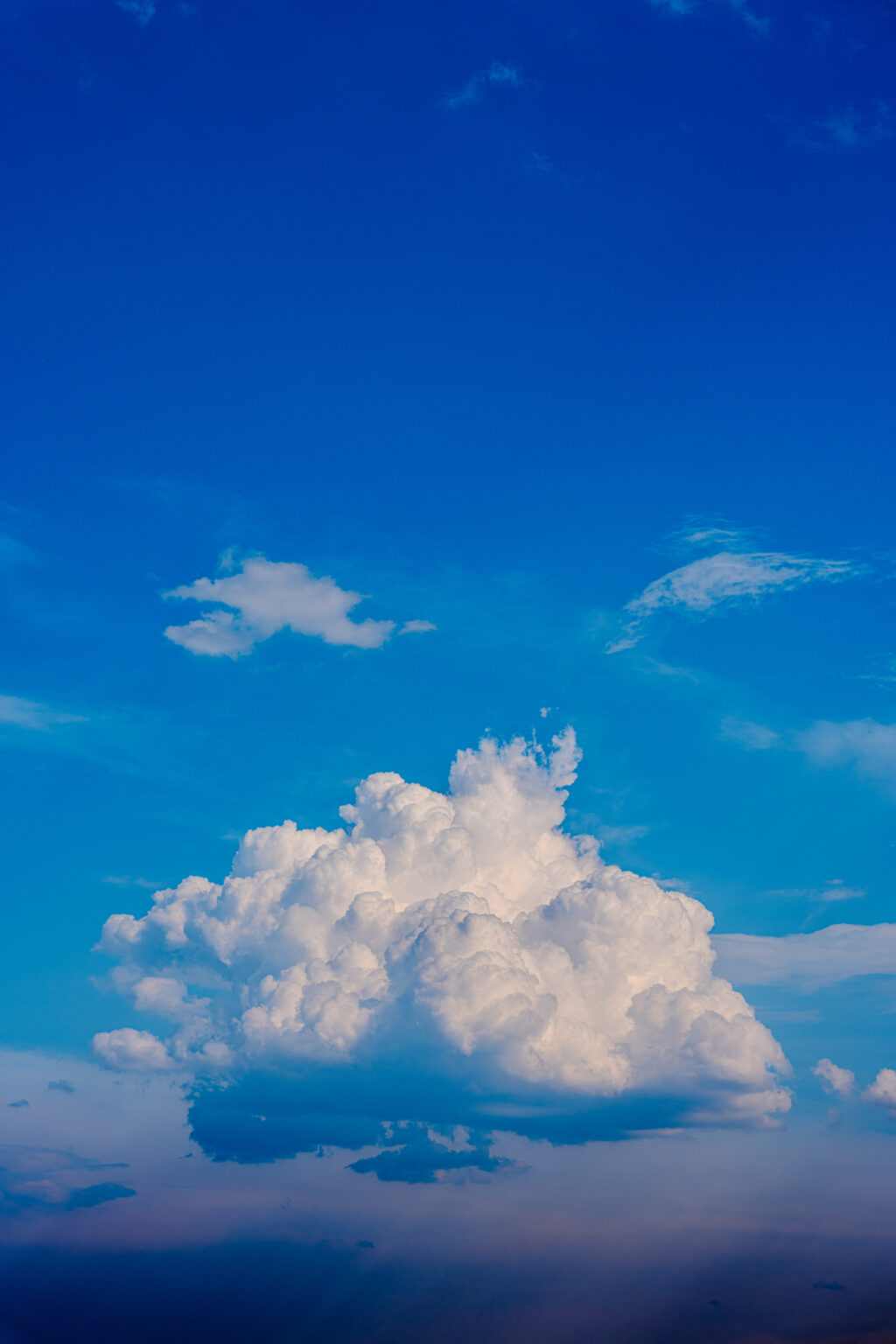 Massive white cloud formation floating in a deep blue sky above the horizon.