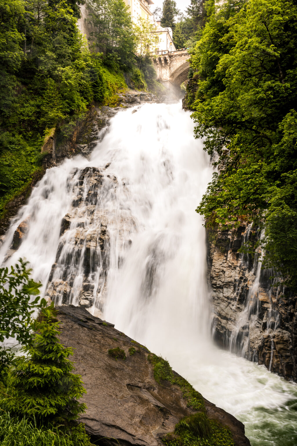 The 341-meter Bad Gastein Waterfall cascading through the historic spa town with the famous Waterfall Bridge and alpine forest, Austria.