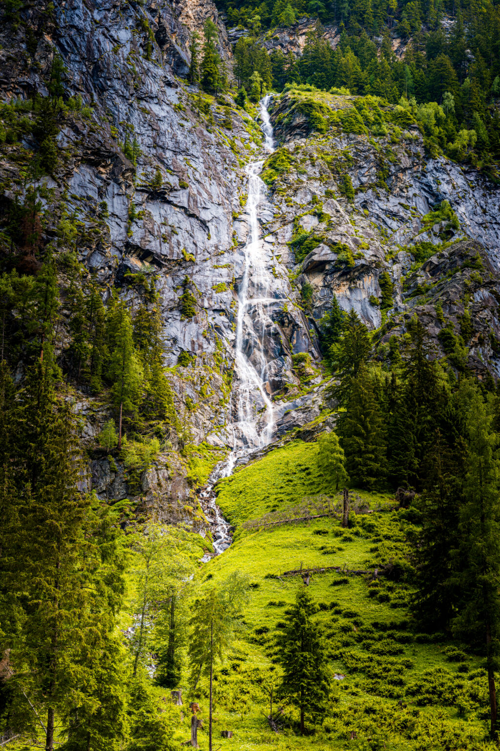 Hidden waterfall cascading down rocky cliffs along the hiking trail to Prossau near Bad Gastein in Hohe Tauern National Park, Austria.