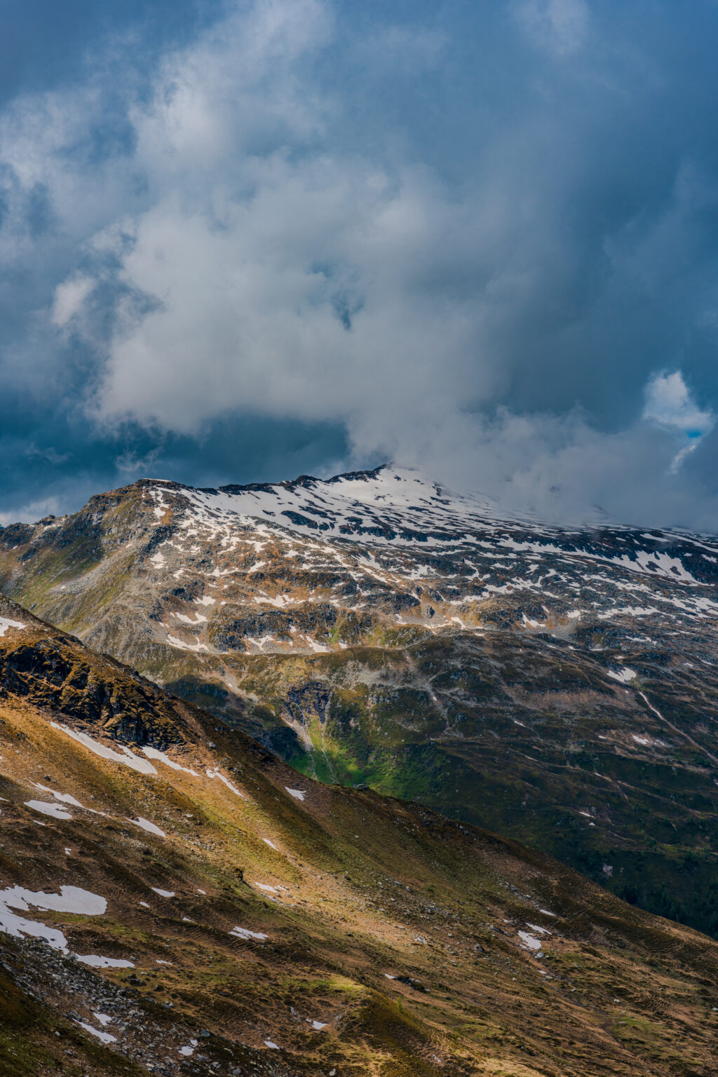 Snow-covered mountain peaks disappearing into dramatic clouds above Stubnerkogel in the Austrian Alps.