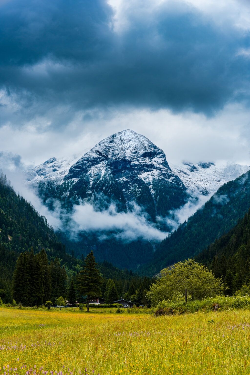 Snow-covered mountain peak emerging from dramatic clouds above the Prossau Valley near Bad Gastein in Hohe Tauern National Park, Austria.