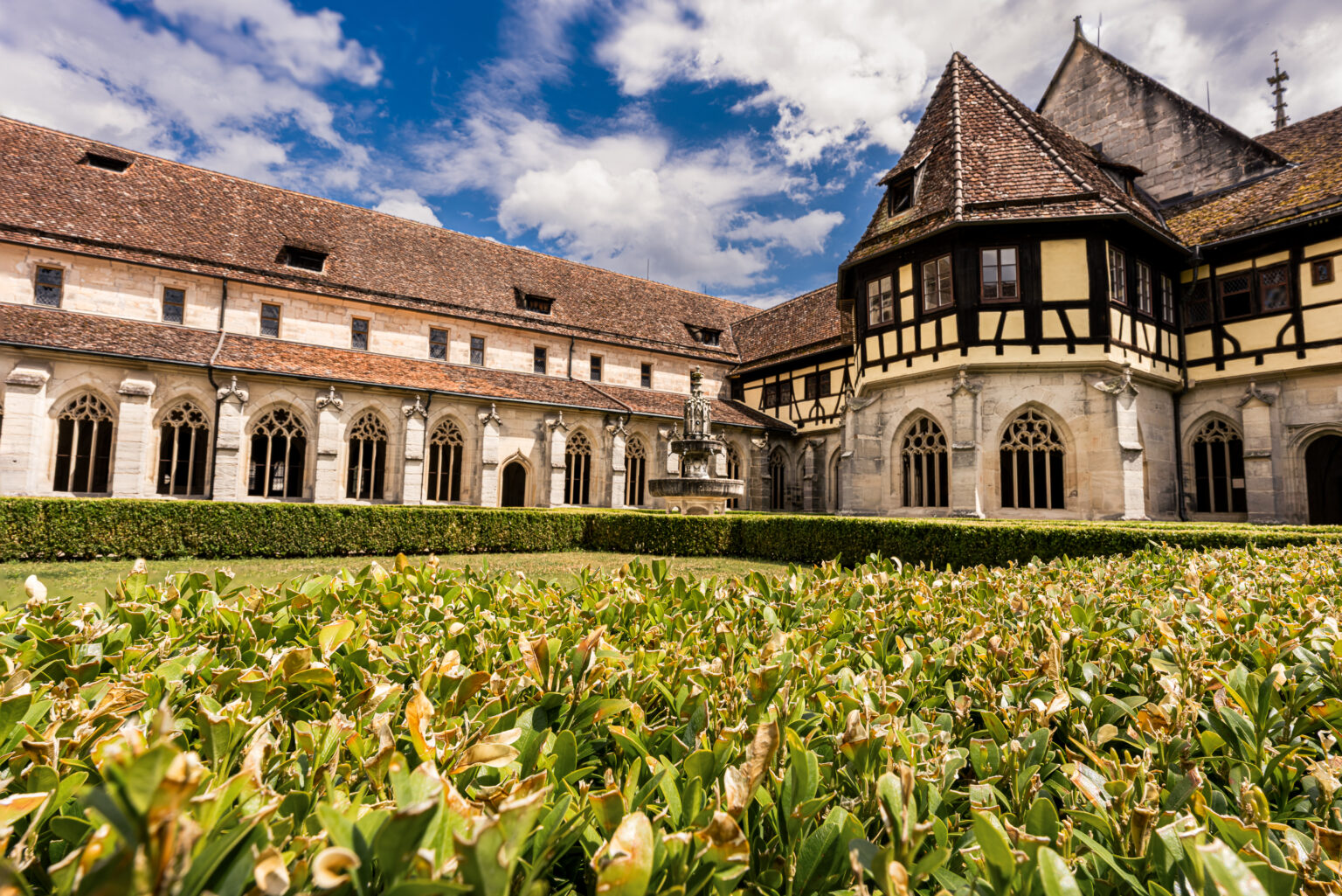 Historic courtyard of Bebenhausen Abbey with Gothic cloisters, medieval fountain, and timber-framed abbot's residence in Baden-Württemberg, Germany.