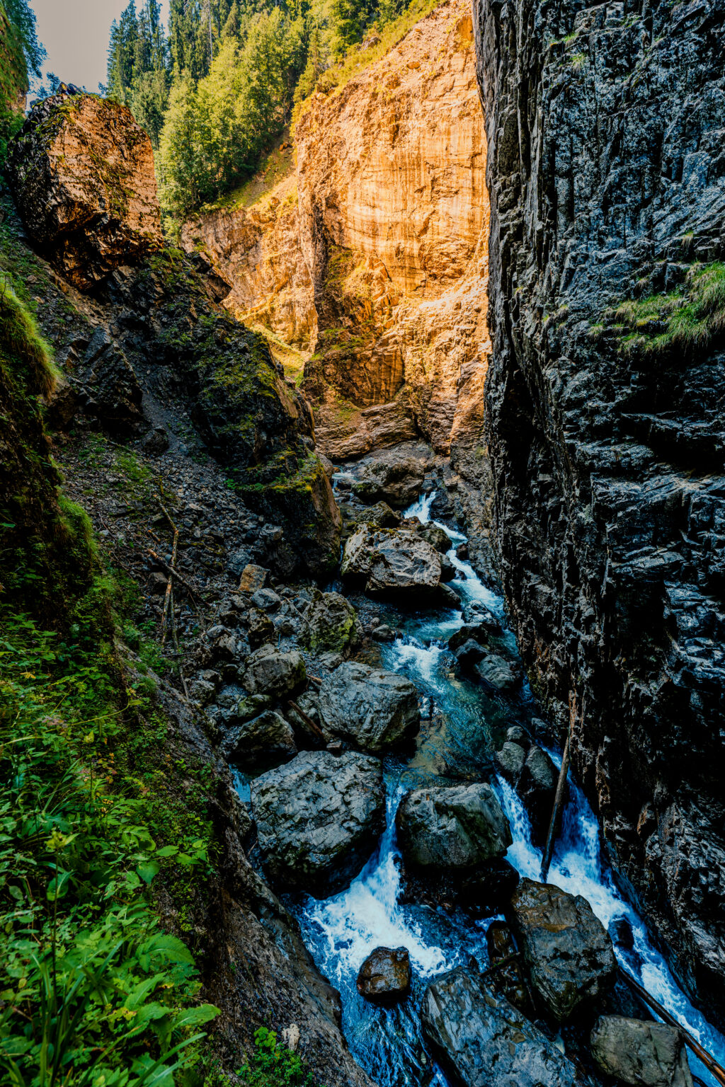 Die Breitach rauscht zwischen gewaltigen Felsen durch die Breitachklamm bei Oberstdorf, während Sonnenlicht die Felswand beleuchtet