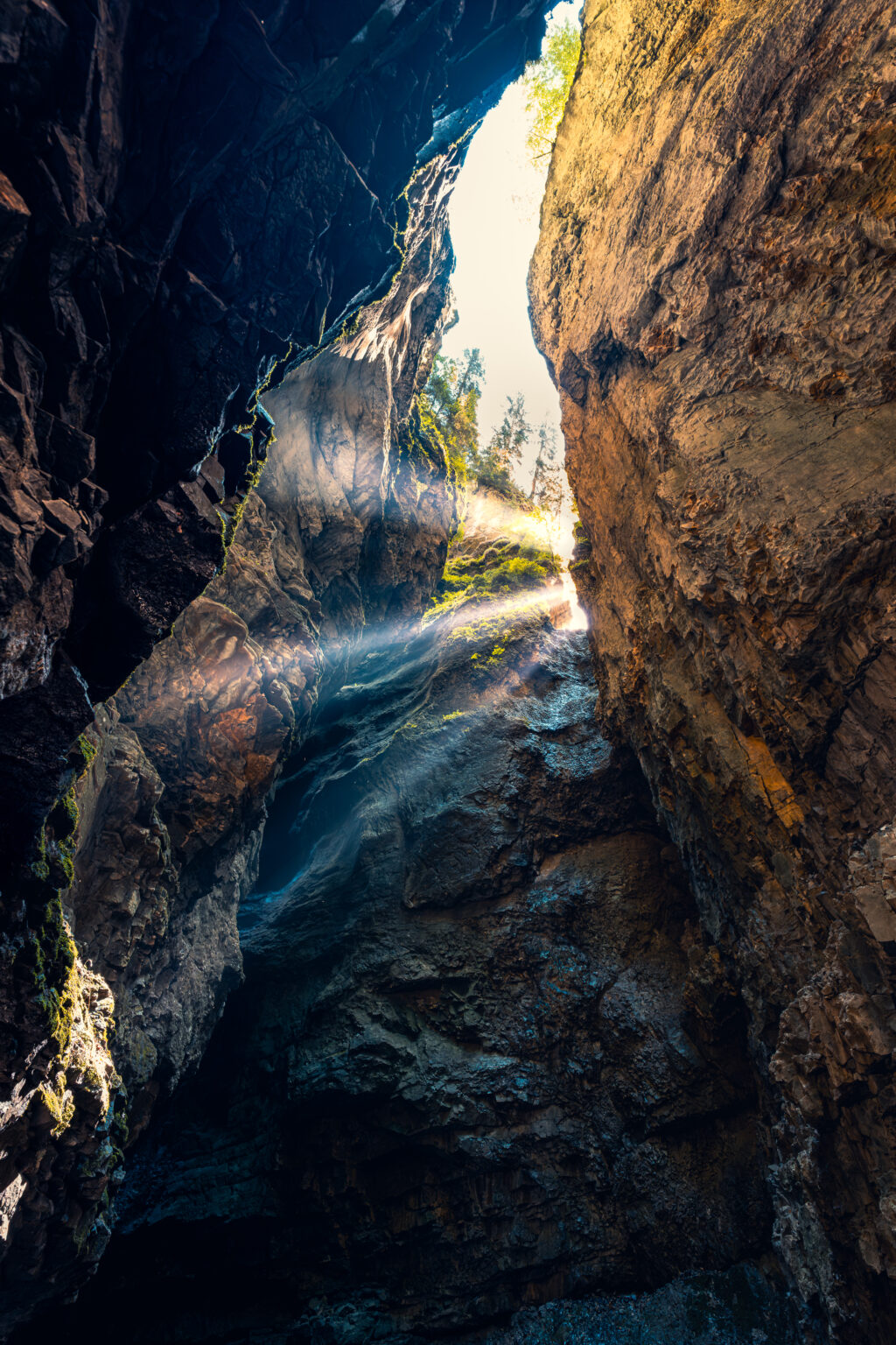 Sonnenstrahlen fallen am frühen Morgen zwischen den hohen Felswänden in die dunkle Breitachklamm bei Oberstdorf